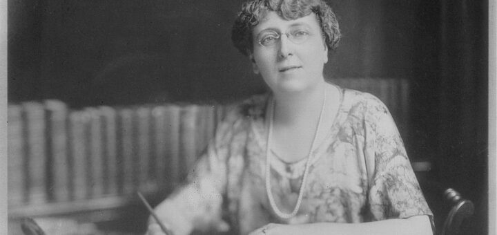 1024px-Portrait_of_Lucy_Maud_Montgomery_at_her_desk_holding_a_pen_I0023627-720×340